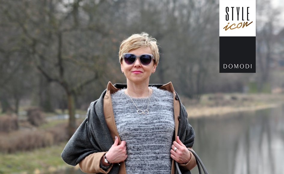 Kobieta w bluzce we wzory i niebieskiej, koronkowej spódnicy.