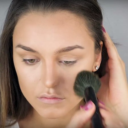 Pudrowanie twarzy pudrem transparentnym przy pomocy dużego pędzla