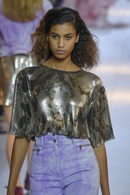 Modelka z pokazu Roberto Cavalli w metalicznej bluzce z animalistycznym printem i fioletowych spodniach.