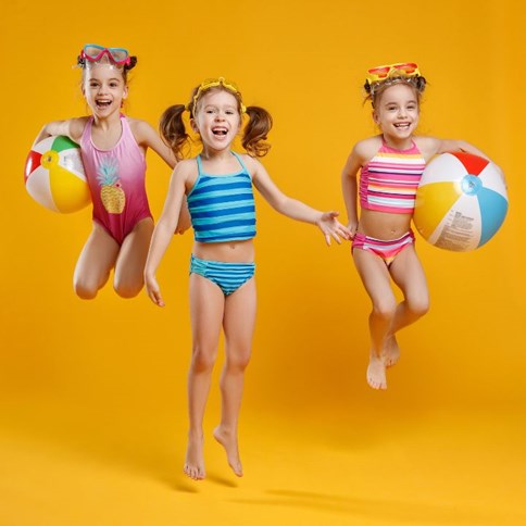 Dziewczynka wbiegająca do morza w ciemnym stroju kąpielowym 