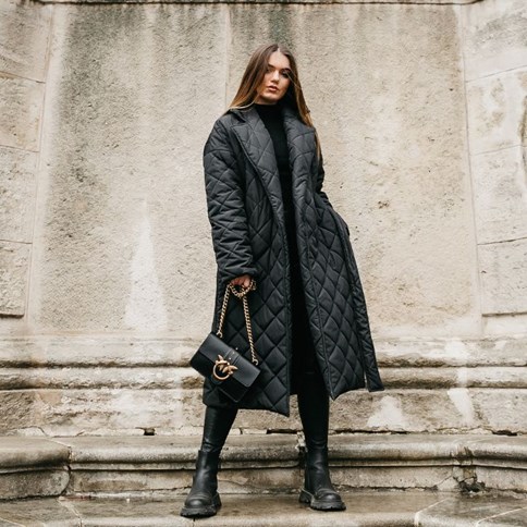 Kobieta w czarnym płaszczu pikowanym 