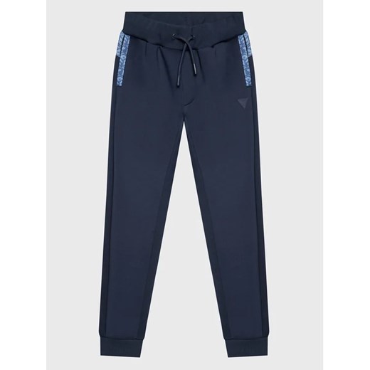 Guess Spodnie dresowe L3RQ15 JR06W Niebieski Relaxed Fit ze sklepu MODIVO w kategorii Spodnie chłopięce - zdjęcie 168451838
