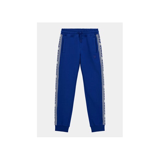 Guess Spodnie dresowe L2YQ48 K6ZS1 Niebieski Regular Fit ze sklepu MODIVO w kategorii Spodnie chłopięce - zdjęcie 168534425
