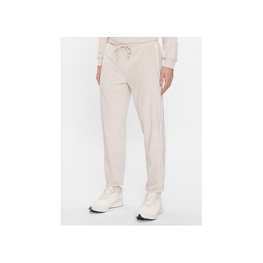 Tommy Hilfiger Spodnie dresowe UM0UM03014 Beżowy Regular Fit ze sklepu MODIVO w kategorii Spodnie męskie - zdjęcie 168663208