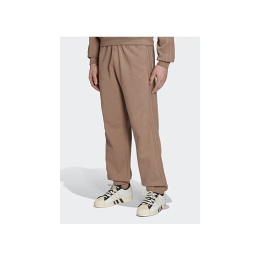 adidas Spodnie dresowe Reveal Essentials HK2727 Brązowy Regular Fit ze sklepu MODIVO w kategorii Spodnie męskie - zdjęcie 168687475