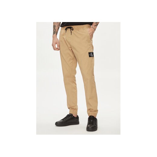 Calvin Klein Jeans Joggery Monologo Badge J30J325114 Beżowy Skinny Fit ze sklepu MODIVO w kategorii Spodnie męskie - zdjęcie 170238355