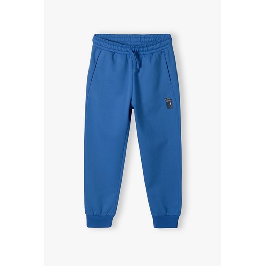 Niebieskie spodnie dresowe regular z kieszeniami dla chłopca ze sklepu 5.10.15 w kategorii Spodnie chłopięce - zdjęcie 170850739