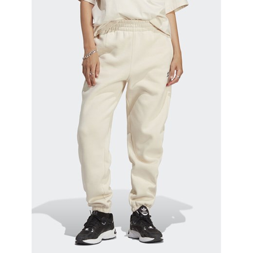 adidas Spodnie dresowe Essentials Fleece IA6436 Écru Regular Fit ze sklepu MODIVO w kategorii Spodnie damskie - zdjęcie 182610948