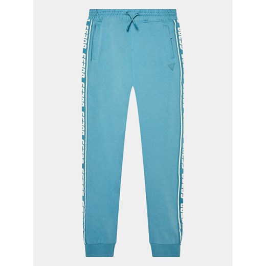 Guess Spodnie dresowe L2YQ48 K6ZS1 Niebieski Regular Fit ze sklepu MODIVO w kategorii Spodnie chłopięce - zdjęcie 182627519