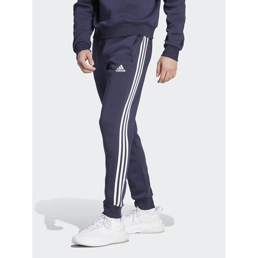 adidas Spodnie dresowe Essentials Fleece 3-Stripes Cuff IJ6493 Granatowy Regular Fit ze sklepu MODIVO w kategorii Spodnie męskie - zdjęcie 182628269