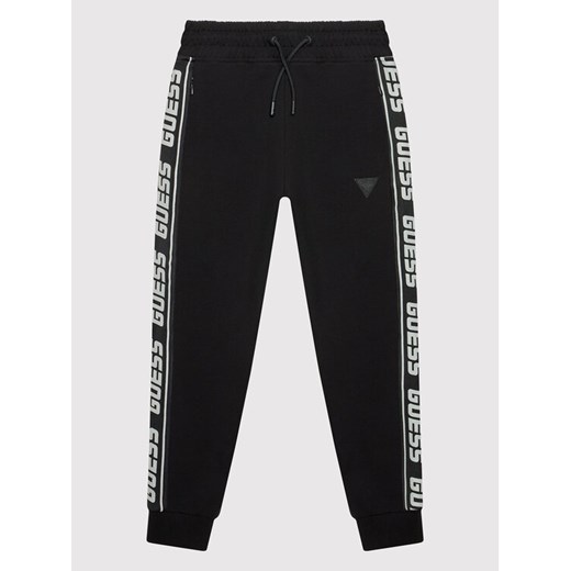Guess Spodnie dresowe L2YQ48 K6ZS1 Czarny Regular Fit ze sklepu MODIVO w kategorii Spodnie chłopięce - zdjęcie 182638345