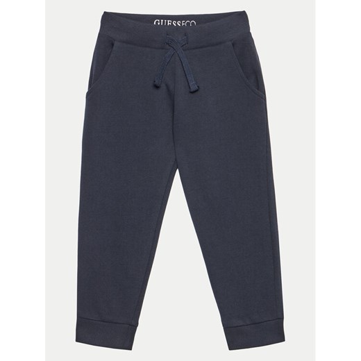 Guess Spodnie dresowe N93Q17 KAUG0 Granatowy Relaxed Fit ze sklepu MODIVO w kategorii Spodnie chłopięce - zdjęcie 182649028