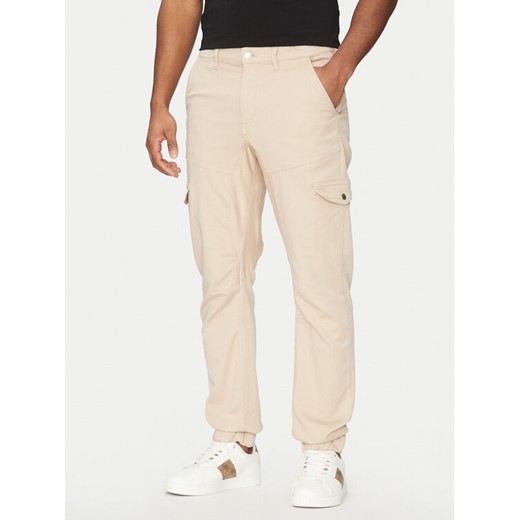 Guess Spodnie materiałowe M5RB54 WGXY1 Beżowy Slim Fit ze sklepu MODIVO w kategorii Spodnie męskie - zdjęcie 182686599