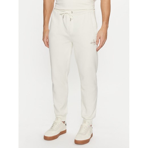 Calvin Klein Jeans Spodnie dresowe Monologo Hwk Pant J30J325658 Écru Regular Fit ze sklepu MODIVO w kategorii Spodnie męskie - zdjęcie 182689166