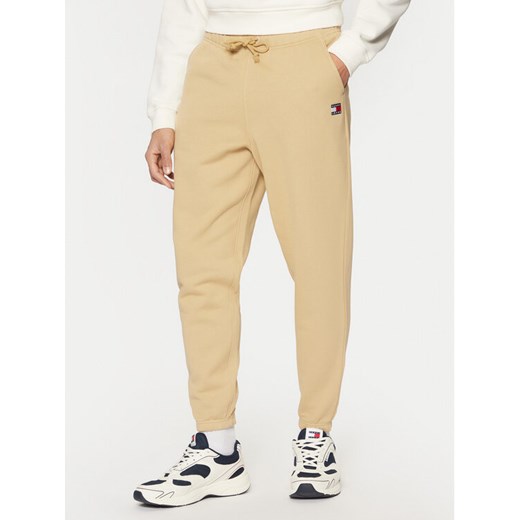 Tommy Jeans Spodnie dresowe Badge DM0DM20276 Beżowy Regular Fit ze sklepu MODIVO w kategorii Spodnie męskie - zdjęcie 182690158