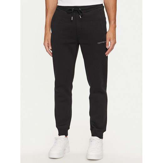 Calvin Klein Jeans Spodnie dresowe Monologo J30J325658 Czarny Regular Fit ze sklepu MODIVO w kategorii Spodnie męskie - zdjęcie 182702336