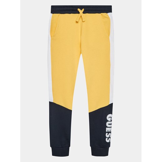 Guess Spodnie dresowe L3BQ11 KAX73 Żółty Regular Fit ze sklepu MODIVO w kategorii Spodnie chłopięce - zdjęcie 182714657