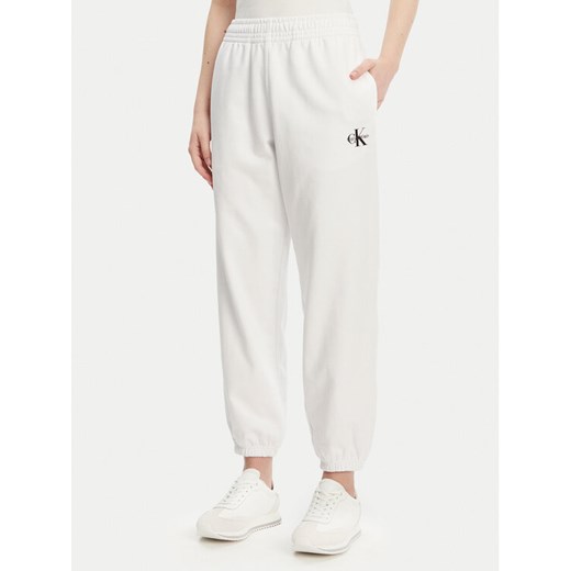 Calvin Klein Jeans Spodnie dresowe Monologo LV047B235G Biały Regular Fit ze sklepu MODIVO w kategorii Spodnie damskie - zdjęcie 182715378
