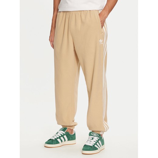 adidas Spodnie dresowe adicolor 3-Stripes IZ2490 Beżowy Regular Fit ze sklepu MODIVO w kategorii Spodnie męskie - zdjęcie 182731285