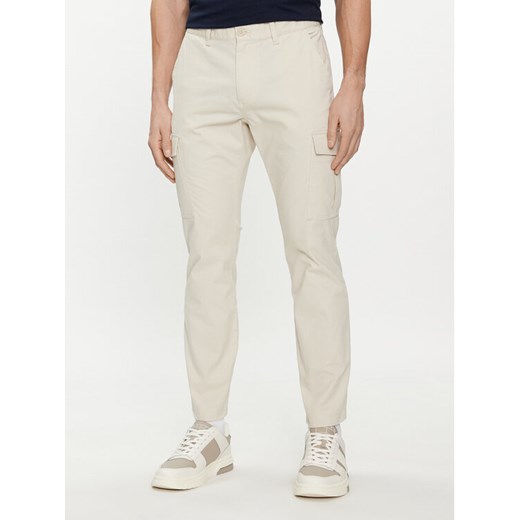 Tommy Jeans Spodnie materiałowe Austin DM0DM18940 Beżowy Slim Fit ze sklepu MODIVO w kategorii Spodnie męskie - zdjęcie 182736016