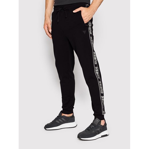 Guess Spodnie dresowe Z2YB19 K6ZS1 Czarny Regular Fit ze sklepu MODIVO w kategorii Spodnie męskie - zdjęcie 182740917