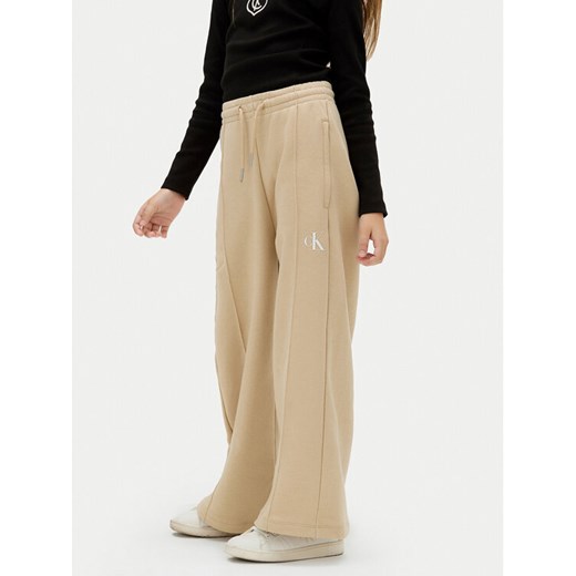 Calvin Klein Jeans Spodnie dresowe IG0IG02875 D Beżowy Wide Leg ze sklepu MODIVO w kategorii Spodnie dziewczęce - zdjęcie 183985378