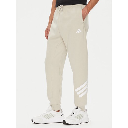 adidas Spodnie dresowe Future Icons 3-Stripes JW7092 Beżowy Regular Fit ze sklepu MODIVO w kategorii Spodnie męskie - zdjęcie 184632578