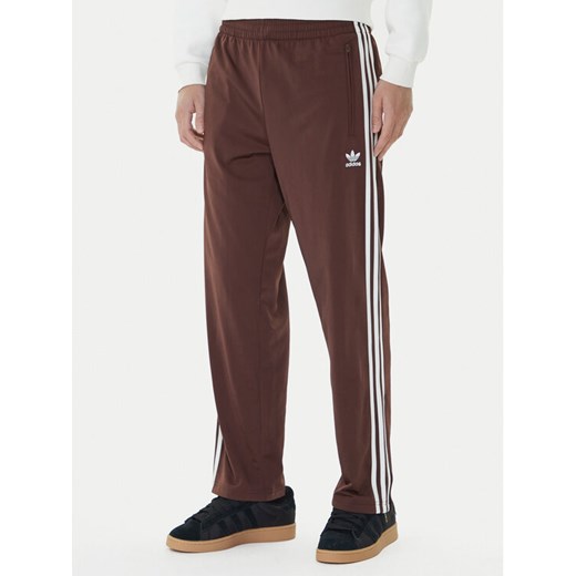 adidas Spodnie dresowe adicolor Classics Firebird KA0482 Brązowy Regular Fit ze sklepu MODIVO w kategorii Spodnie męskie - zdjęcie 185869629