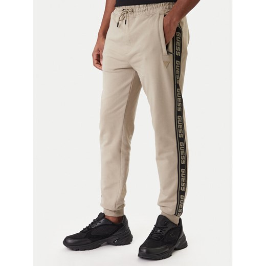 Guess Spodnie dresowe Z2YB19 K6ZS1 Beżowy Regular Fit ze sklepu MODIVO w kategorii Spodnie męskie - zdjęcie 187976037