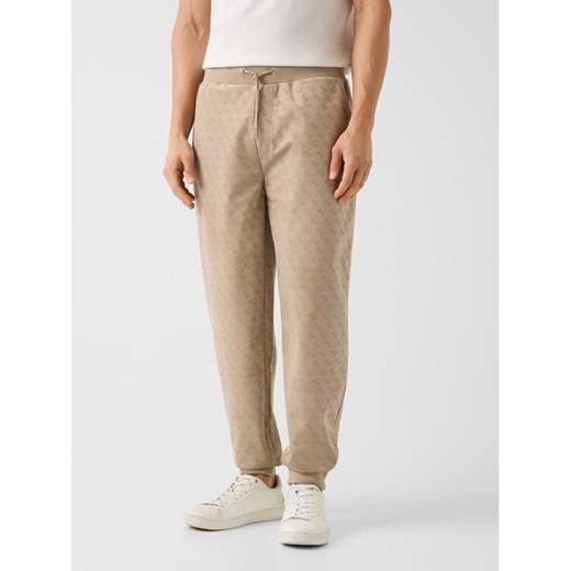 Guess Spodnie materiałowe 180800 Beżowy Regular Fit ze sklepu MODIVO w kategorii Spodnie męskie - zdjęcie 188013247