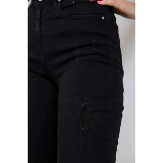 Czarne jeansowe spodnie z przetarciami oraz szarpaniem na dole nogawki    olika.com.pl