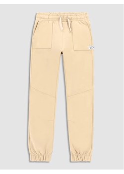 Coccodrillo Spodnie dresowe WC3120103SKK Beżowy Slim Fit ze sklepu MODIVO w kategorii Spodnie chłopięce - zdjęcie 168378329