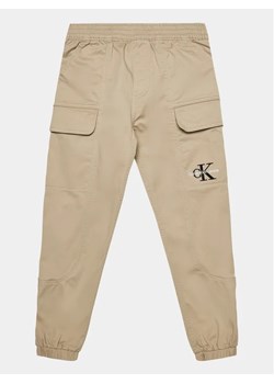 Calvin Klein Jeans Joggery IB0IB01675 Beżowy Regular Fit ze sklepu MODIVO w kategorii Spodnie chłopięce - zdjęcie 168415675