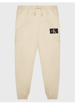 Calvin Klein Jeans Spodnie dresowe IB0IB01505 Beżowy Regular Fit ze sklepu MODIVO w kategorii Spodnie dziewczęce - zdjęcie 168431697