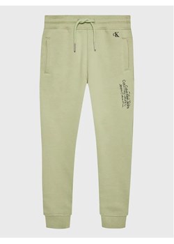 Calvin Klein Jeans Spodnie dresowe Repeat Inst. Logo IB0IB01568 Zielony Regular Fit ze sklepu MODIVO w kategorii Spodnie chłopięce - zdjęcie 168490488