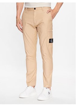 Calvin Klein Jeans Spodnie materiałowe J30J323508 Beżowy Regular Fit ze sklepu MODIVO w kategorii Spodnie męskie - zdjęcie 168510799