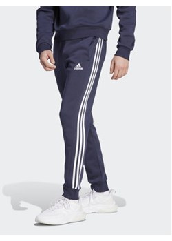 adidas Spodnie dresowe Essentials Fleece 3-Stripes Cuff IJ6493 Granatowy Regular Fit ze sklepu MODIVO w kategorii Spodnie męskie - zdjęcie 168543557