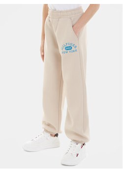Tommy Hilfiger Spodnie dresowe Varsity KG0KG07605 Beżowy Regular Fit ze sklepu MODIVO w kategorii Spodnie chłopięce - zdjęcie 168552567