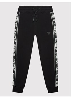 Guess Spodnie dresowe L2YQ48 K6ZS1 Czarny Regular Fit ze sklepu MODIVO w kategorii Spodnie chłopięce - zdjęcie 168554775