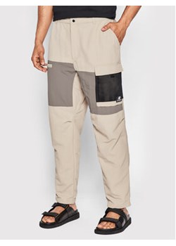 New Balance Spodnie materiałowe MP21502 Beżowy Relaxed Fit ze sklepu MODIVO w kategorii Spodnie męskie - zdjęcie 168563486