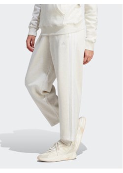 adidas Spodnie dresowe Essentials 3-Stripes Open Hem Fleece IM0248 Écru Loose Fit ze sklepu MODIVO w kategorii Spodnie damskie - zdjęcie 168638538