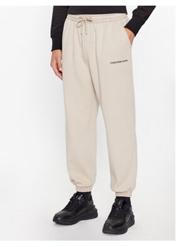 Calvin Klein Jeans Spodnie dresowe J30J322925 Écru Relaxed Fit ze sklepu MODIVO w kategorii Spodnie męskie - zdjęcie 168658588