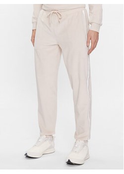 Tommy Hilfiger Spodnie dresowe UM0UM03014 Beżowy Regular Fit ze sklepu MODIVO w kategorii Spodnie męskie - zdjęcie 168663208
