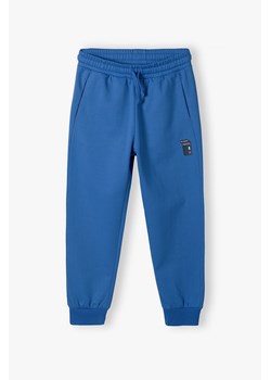 Niebieskie spodnie dresowe regular z kieszeniami dla chłopca ze sklepu 5.10.15 w kategorii Spodnie chłopięce - zdjęcie 170850739