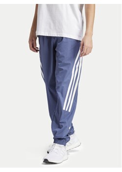 adidas Spodnie dresowe Future Icons 3-Stripes IR9239 Niebieski Slim Fit ze sklepu MODIVO w kategorii Spodnie męskie - zdjęcie 170918949
