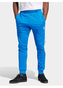 adidas Spodnie dresowe adicolor Classics SST IM4542 Niebieski Slim Fit ze sklepu MODIVO w kategorii Spodnie męskie - zdjęcie 171449416