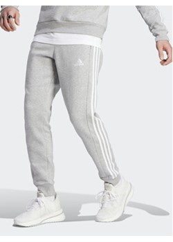 adidas Spodnie dresowe Essentials Fleece 3-Stripes Cuff IJ6494 Szary Regular Fit ze sklepu MODIVO w kategorii Spodnie męskie - zdjęcie 171596475