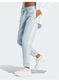 adidas Spodnie dresowe Future Icons 3-Stripes IM2545 Błękitny Regular Fit ze sklepu MODIVO w kategorii Spodnie damskie - zdjęcie 172390118