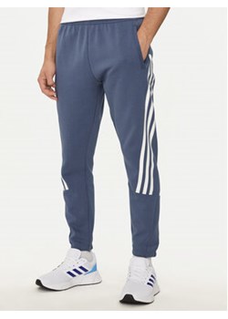 adidas Spodnie dresowe Future Icons 3-Stripes IR9194 Niebieski Slim Fit ze sklepu MODIVO w kategorii Spodnie męskie - zdjęcie 176611959