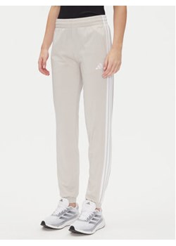 adidas Spodnie dresowe Tricot 3-Stripes JD4536 Beżowy Regular Fit ze sklepu MODIVO w kategorii Spodnie damskie - zdjęcie 179131048